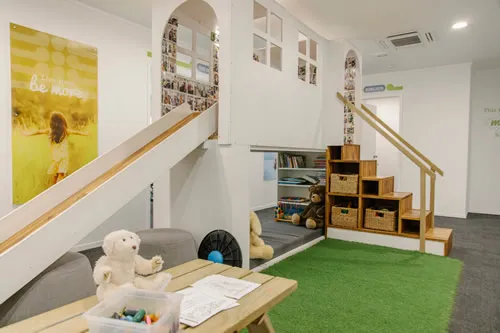 The practice’s kids’ corner, with a slide, play steps and a green play mat